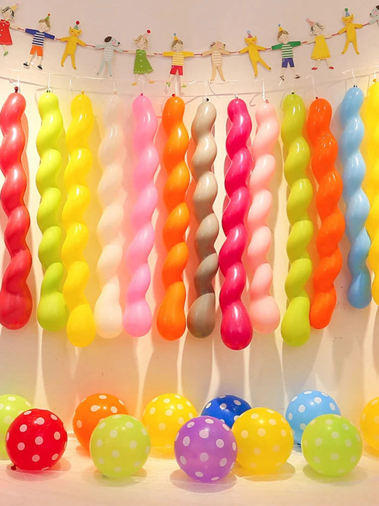Assorted latex balloons in various colors like pink, yellow, green, and orange are displayed hanging and on the ground.
