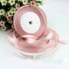 Pink silk satin ribbon roll with white filling and loose ribbons on a white background
