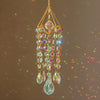 A hanging crystal rainbow wind chime featuring a central faceted stone and multiple dangling glass beads.