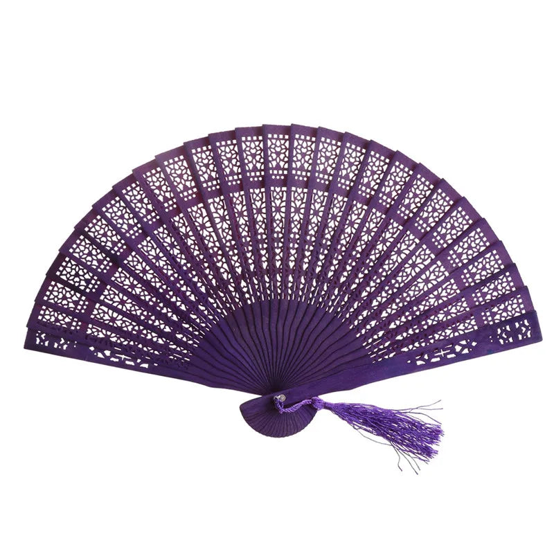 A purple hand carved bamboo folding fan with intricate lattice work and a tassel.