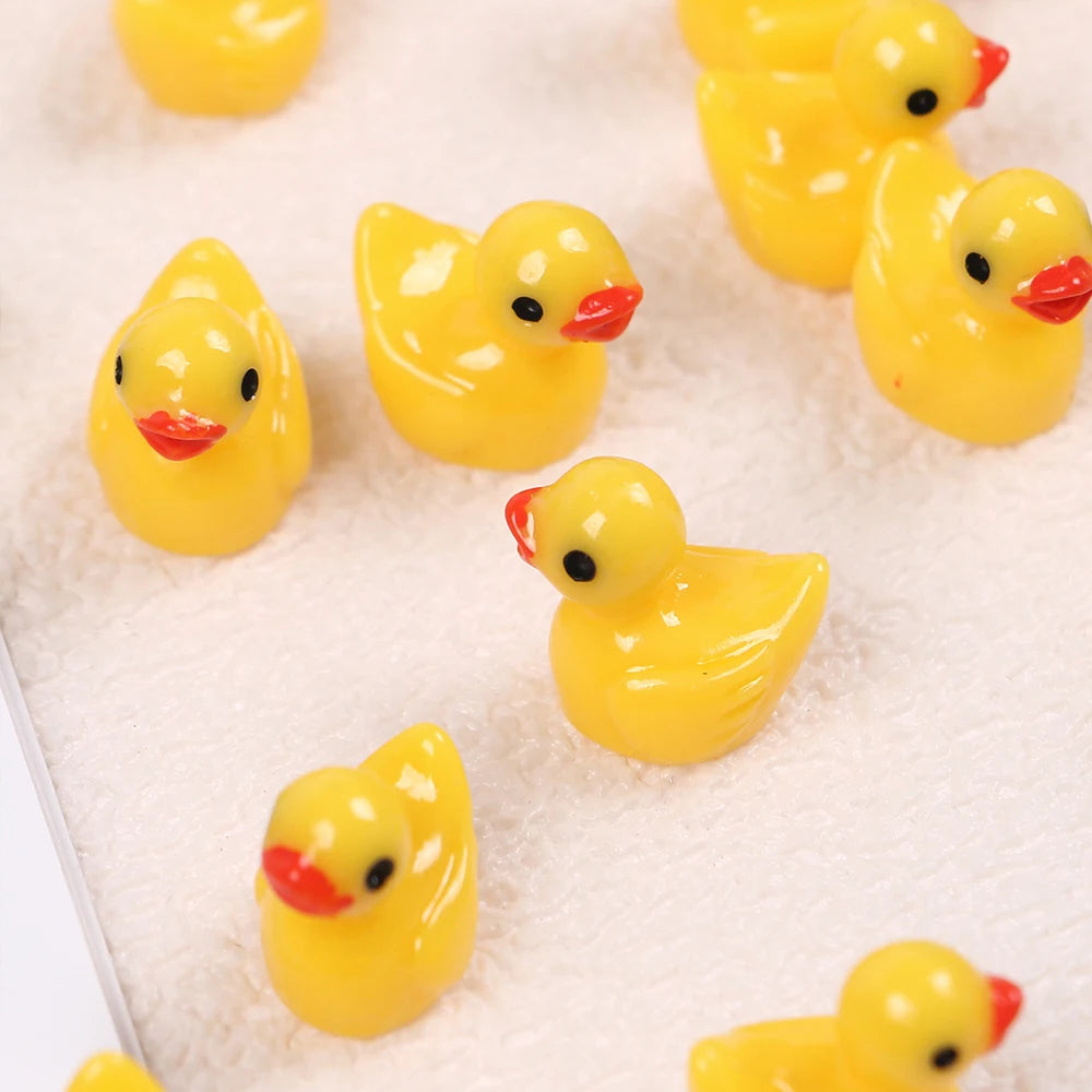 A collection of small yellow resin duck figurines arranged on a white textured surface.