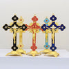 A set of four antique-style crucifix figurines with gold and colored crosses on black stands.