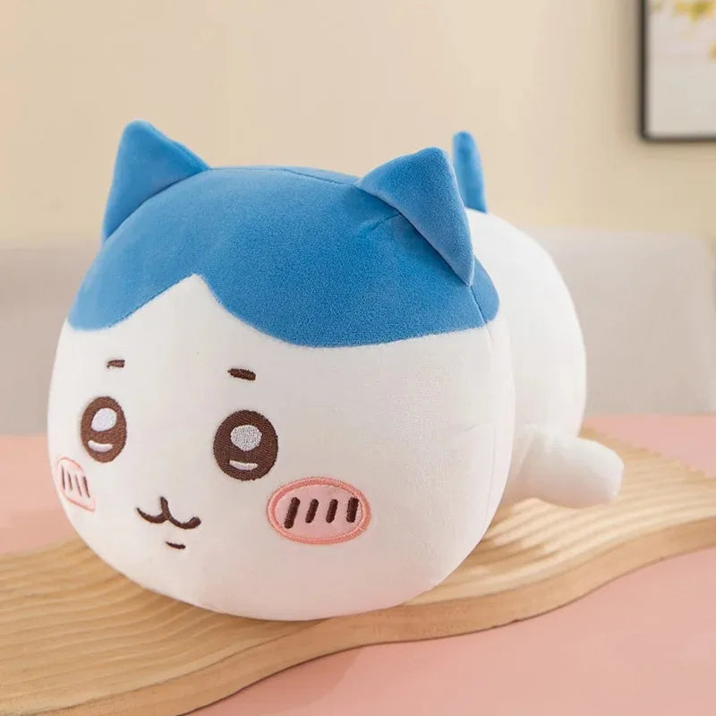A soft blue and white Chiikawa Hachiware plush pillow with large eyes and pointed ears resting on a wooden surface.