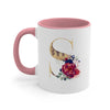 A pink ceramic coffee mug featuring a gold letter S design and floral accents.