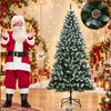 A flocked artificial Christmas tree decorated with warm white LED lights standing next to a Santa figure.