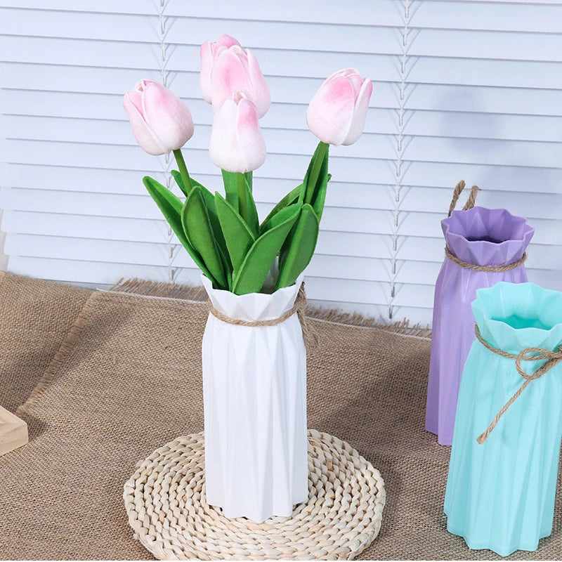 Modern white plastic vase with a basket design holding pink tulips on a woven mat.