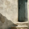 A weathered light blue wooden door set into a pale stucco wall with stone steps.