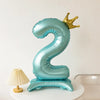 A light blue foil balloon shaped like the number two with a gold crown on top.
