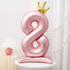 A pink foil balloon shaped like the number 8 with a gold crown on top