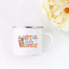 A white enamel mug with the text Coffee Teach Repeat in pink and yellow floral script.