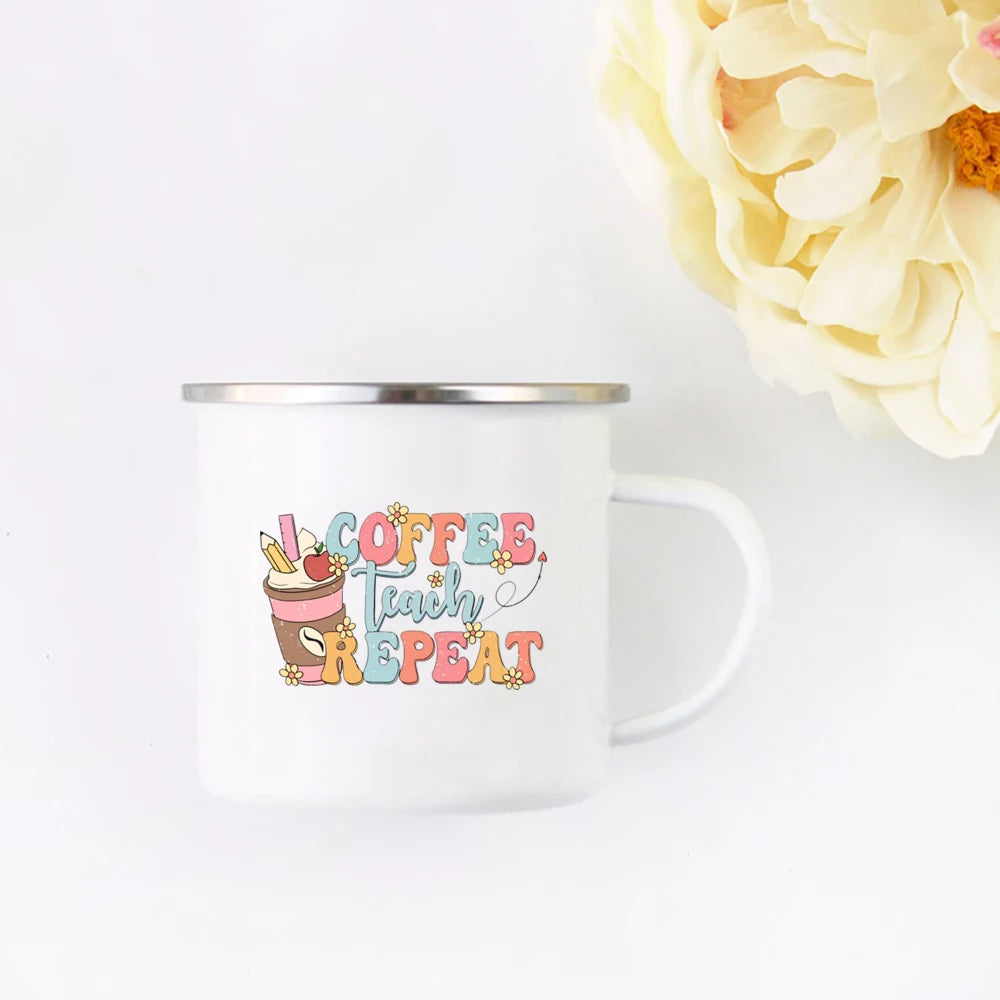 A white enamel mug with the text Coffee Teach Repeat in pink and yellow floral script.