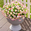 A potted arrangement of pink and white morning glory flowers and eucalyptus stems in a gray urn on a wooden deck.