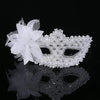 White feather rhinestone masquerade mask displayed on a reflective surface against a black background.