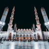 Night view of the Masjid an Nabawi with minarets and dome architecture.