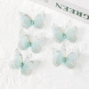 A set of light blue translucent butterfly patches with silver accents displayed on white lace fabric.