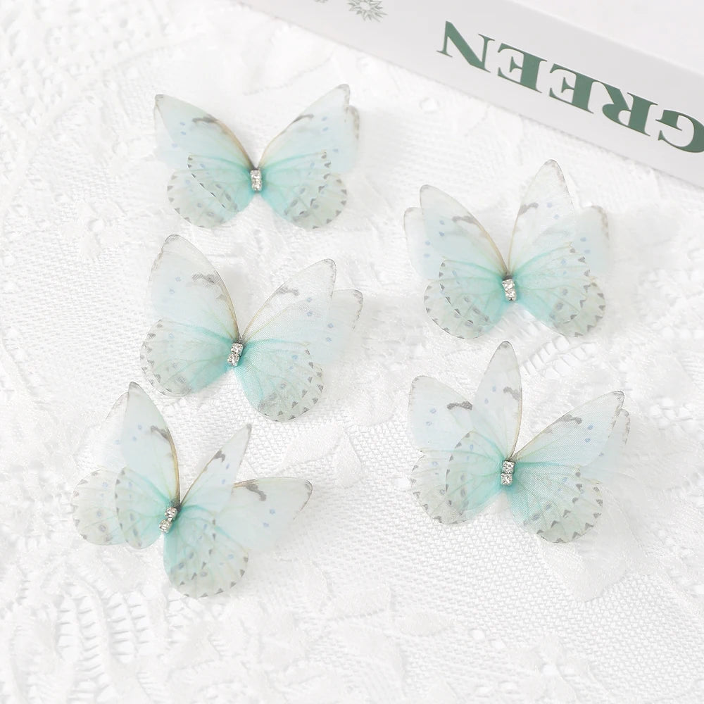A set of light blue translucent butterfly patches with silver accents displayed on white lace fabric.