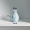 A light blue ceramic mini vase with a narrow neck and rounded body, shown against a white background.
