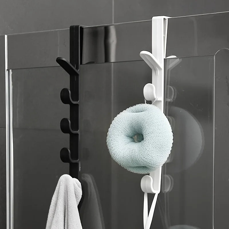 A close-up of white over-the-door hooks holding a light blue knitted sphere on a glass door.