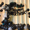 A large balloon arch decorated with black and silver latex balloons spelling out HAPPY BIRTHDAY
