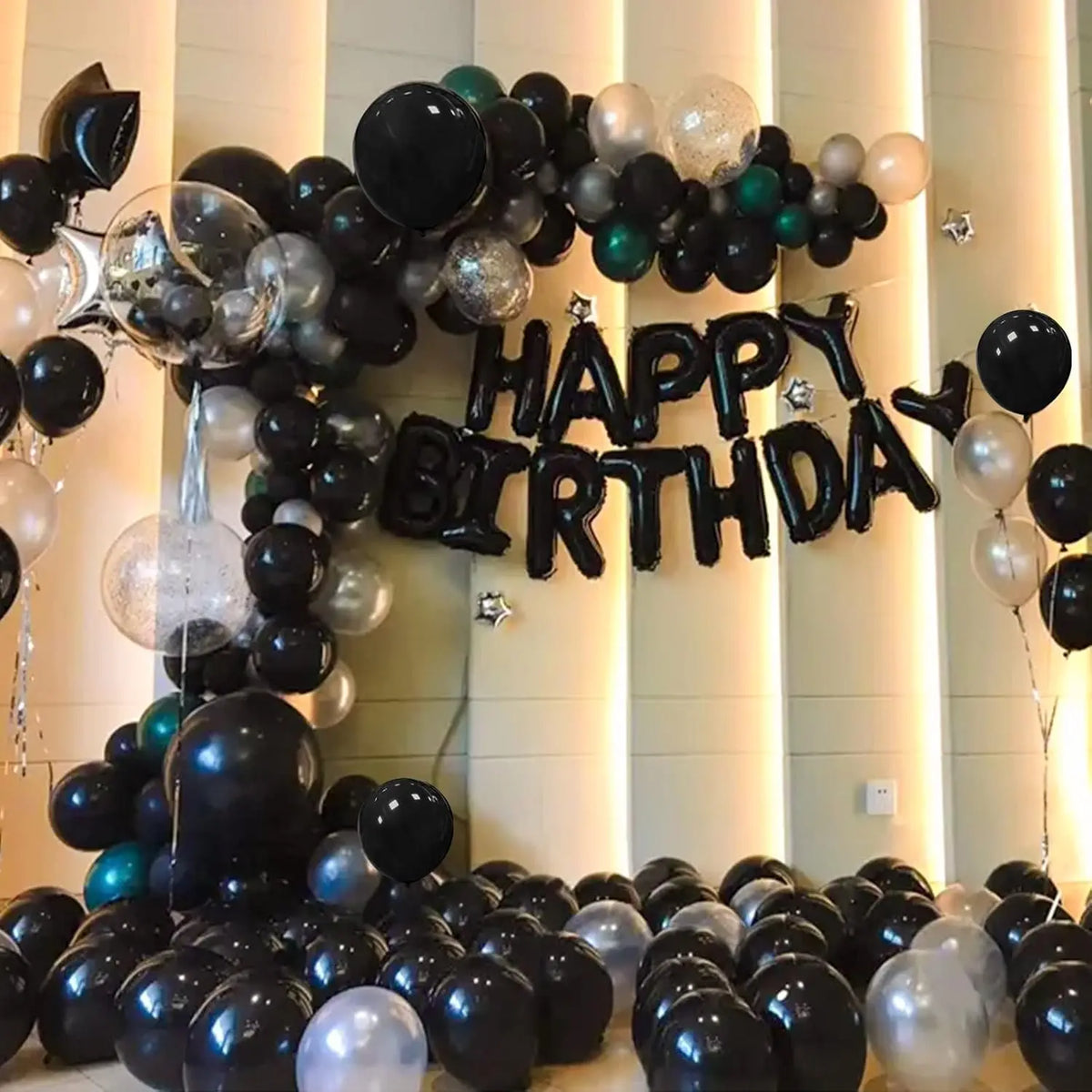 A large balloon arch decorated with black and silver latex balloons spelling out HAPPY BIRTHDAY