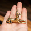A vintage brass pharaoh hound statue, inspired by Egyptian motifs, resting on a person's hand.