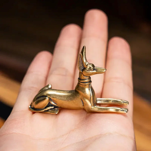 A vintage brass pharaoh hound statue, inspired by Egyptian motifs, resting on a person's hand.