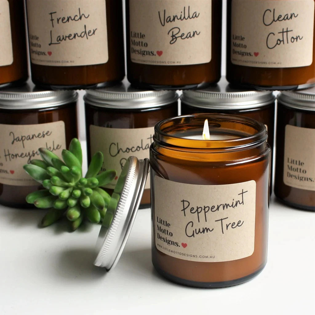 A collection of amber glass jars with airtight lids and labels for scented candles, including a jar labeled Peppermint Gum Tr