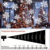 A projection light casts white snowflakes onto a Christmas tree and surrounding decor.
