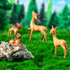 A set of small deer figurines in various poses standing on green grass and a rock.