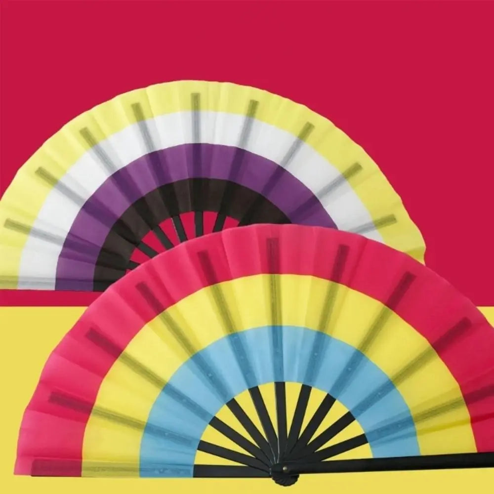 A colorful folding hand fan with rainbow stripes in yellow, purple, and pink against a red background.