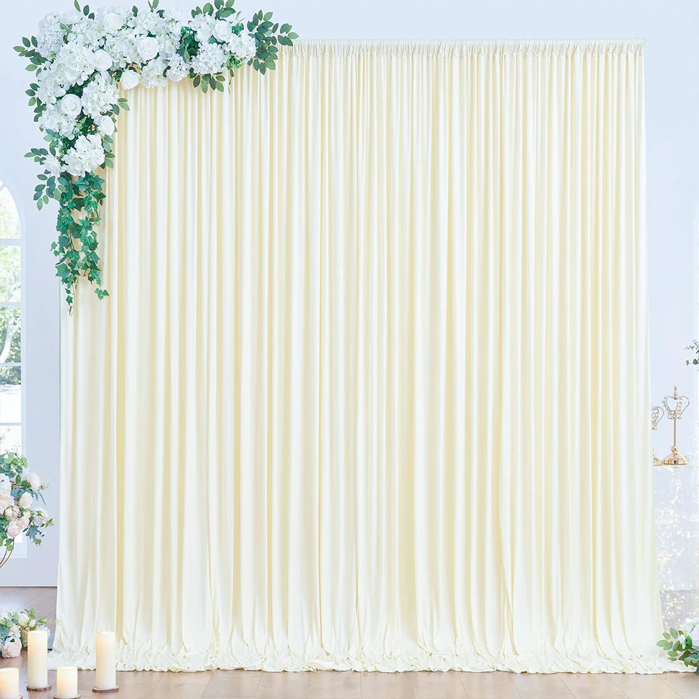 A floor-to-ceiling cream fabric backdrop with vertical pleats and greenery accents.
