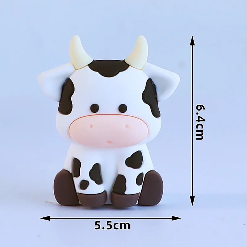 A white and black cow-shaped decoration with pink accents, measuring 6.4 cm in height.