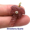A pink strawberry quartz pendant with a gold bail is held by a person's finger.