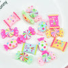 A collection of colorful resin candy cabochons in various shapes and colors arranged on a white surface.