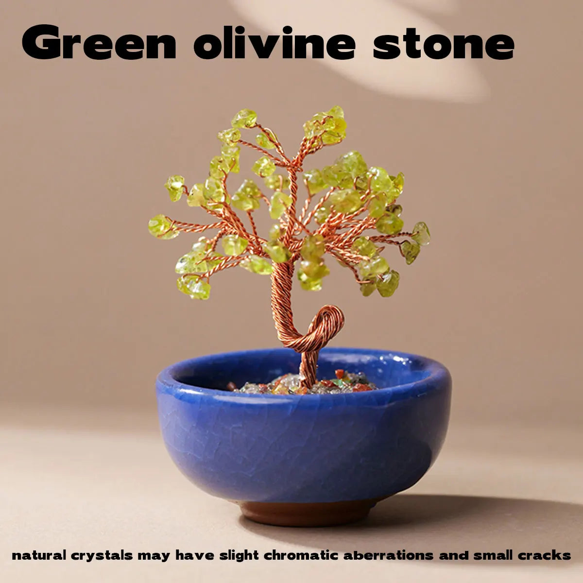 A handcrafted green olivine stone crystal tree with a copper wire base set in a blue bowl.