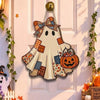 A wooden ghost door hanging with a witch hat design, featuring patchwork fabric and an orange pumpkin.