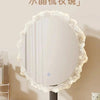 A round cream mirror with a ruffled edge and a black base, displayed on a light surface.