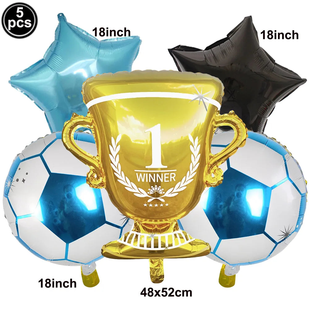 A gold trophy balloon surrounded by soccer balls and a black balloon, used for party decoration.