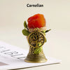A natural crystal brass bell with a copper finish, decorated with green leaves and presented on a white surface.