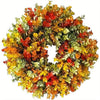 A dense wreath of artificial flowers in shades of orange, yellow, and green for home decor