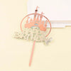 A gold-colored princess castle cake topper set featuring a castle silhouette and happy birthday text on a wooden stick.