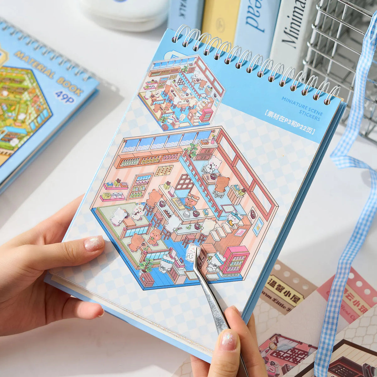 A hand holds a sticker book featuring miniature 3D scenes for kids, showing colorful scenes and stickers.