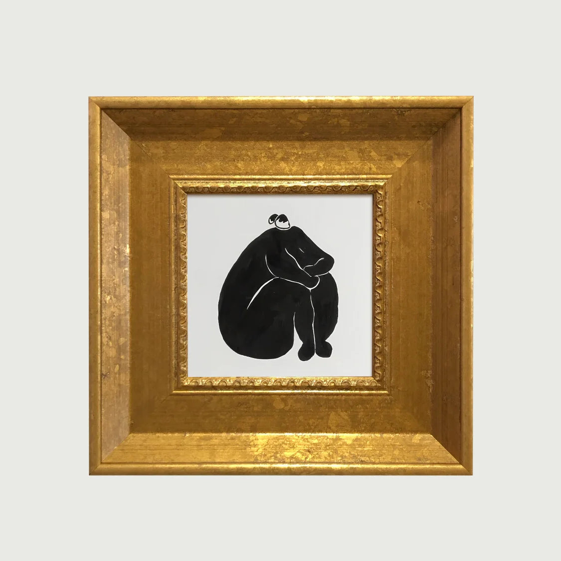 An elegant gold photo frame with a black silhouette of a person sitting.