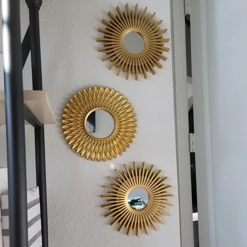 A set of three gold sunflower wall mirrors mounted on a white wall.