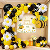 A balloon arch set featuring yellow, black, and white balloons shaped like bees and daisies.