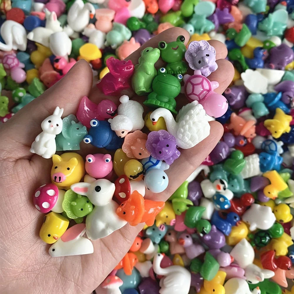 A hand holds a large collection of assorted resin miniature figurines in various colors and shapes for DIY decor.
