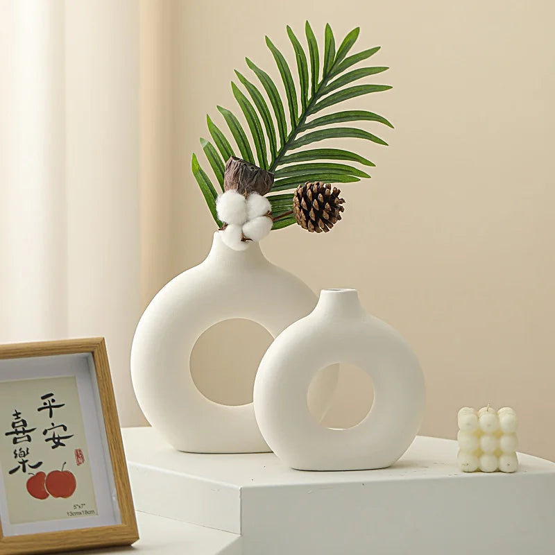 White ceramic vase with a donut pattern decorated with green palm leaves and pine cones.