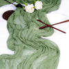 Sage green gauze fabric draped elegantly with white roses on a white plate.