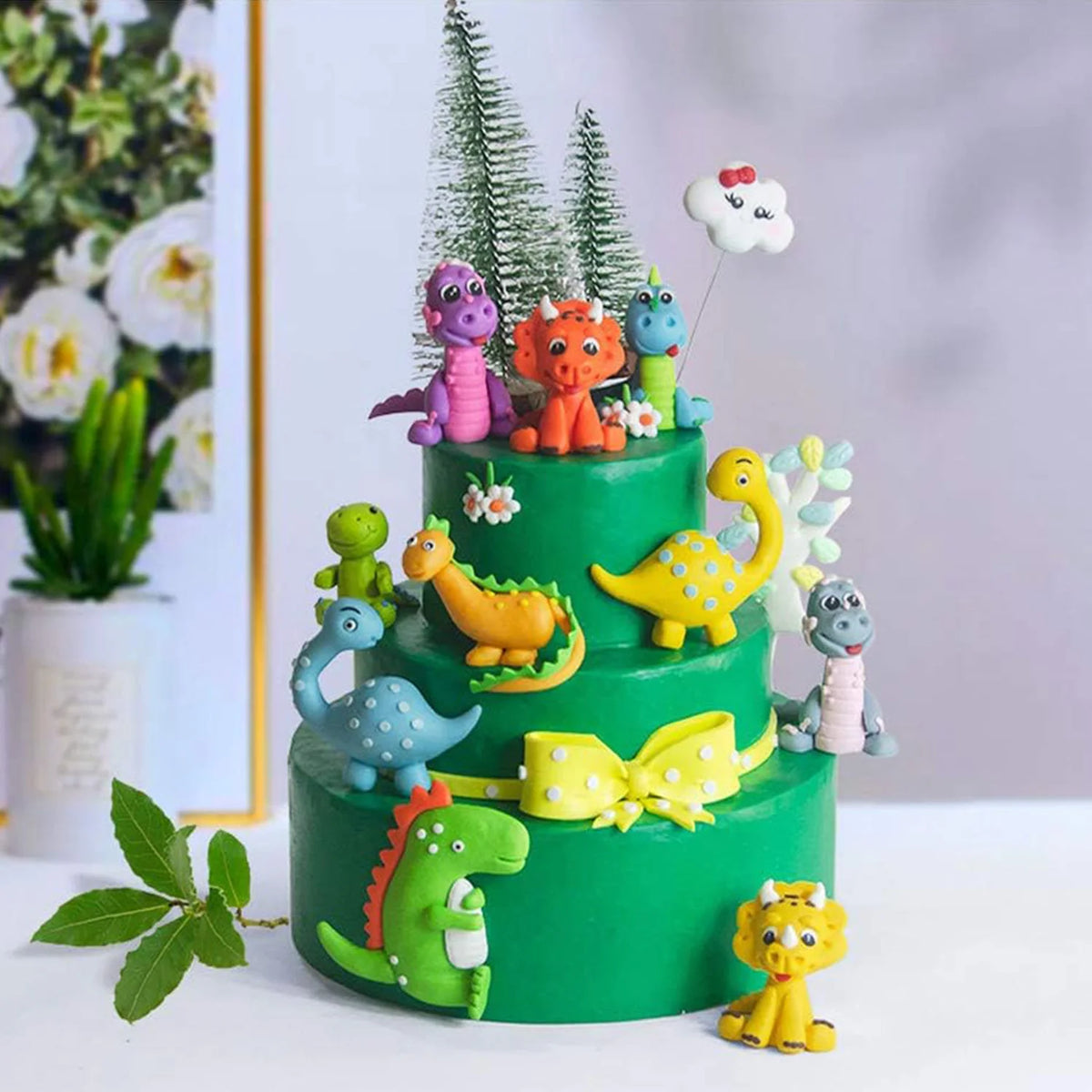 Pastel de varios niveles decorado con figuras de dinosaurios coloridos y glaseado verde.