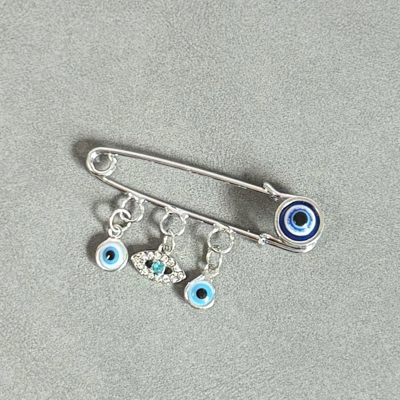 An elegant gold and silver evil eye brooch pin featuring multiple blue and white glass eyes.